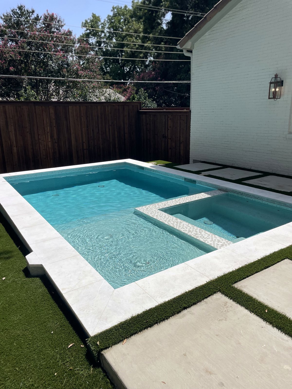 Close-up of the spa with mosaic tile edge, clear blue water and bright white stone coping โ completed by Infinity Group DFW in Dallas, Texas